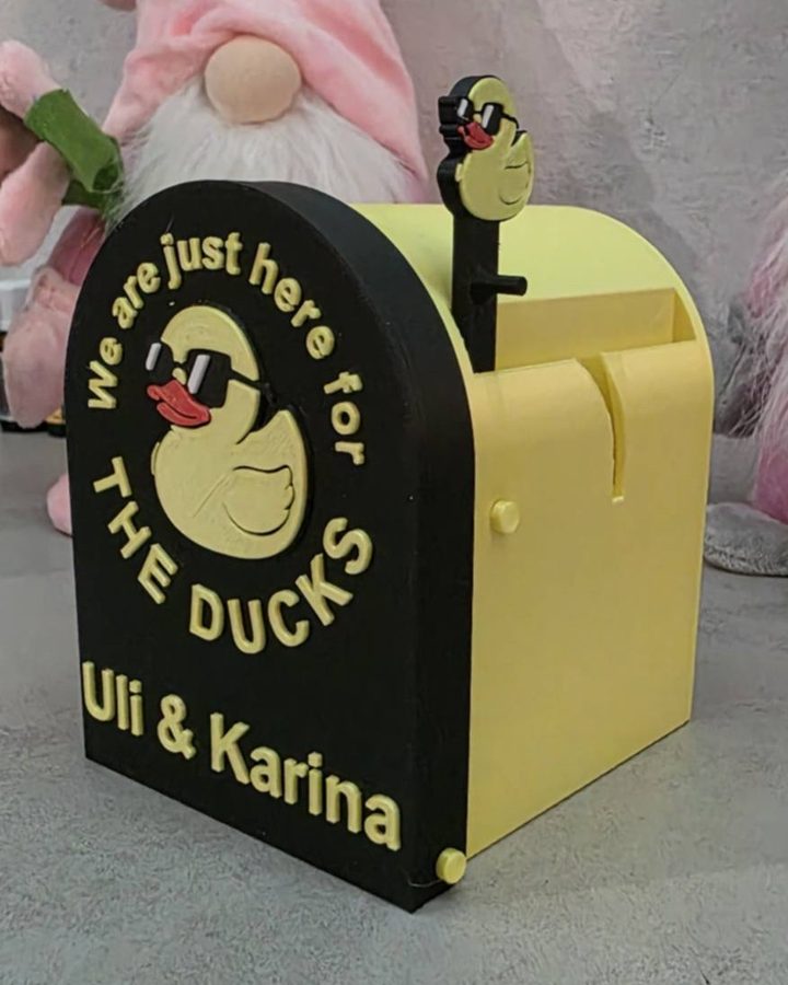 Gelber Briefkasten mit Ente und aufgedruckten Namen